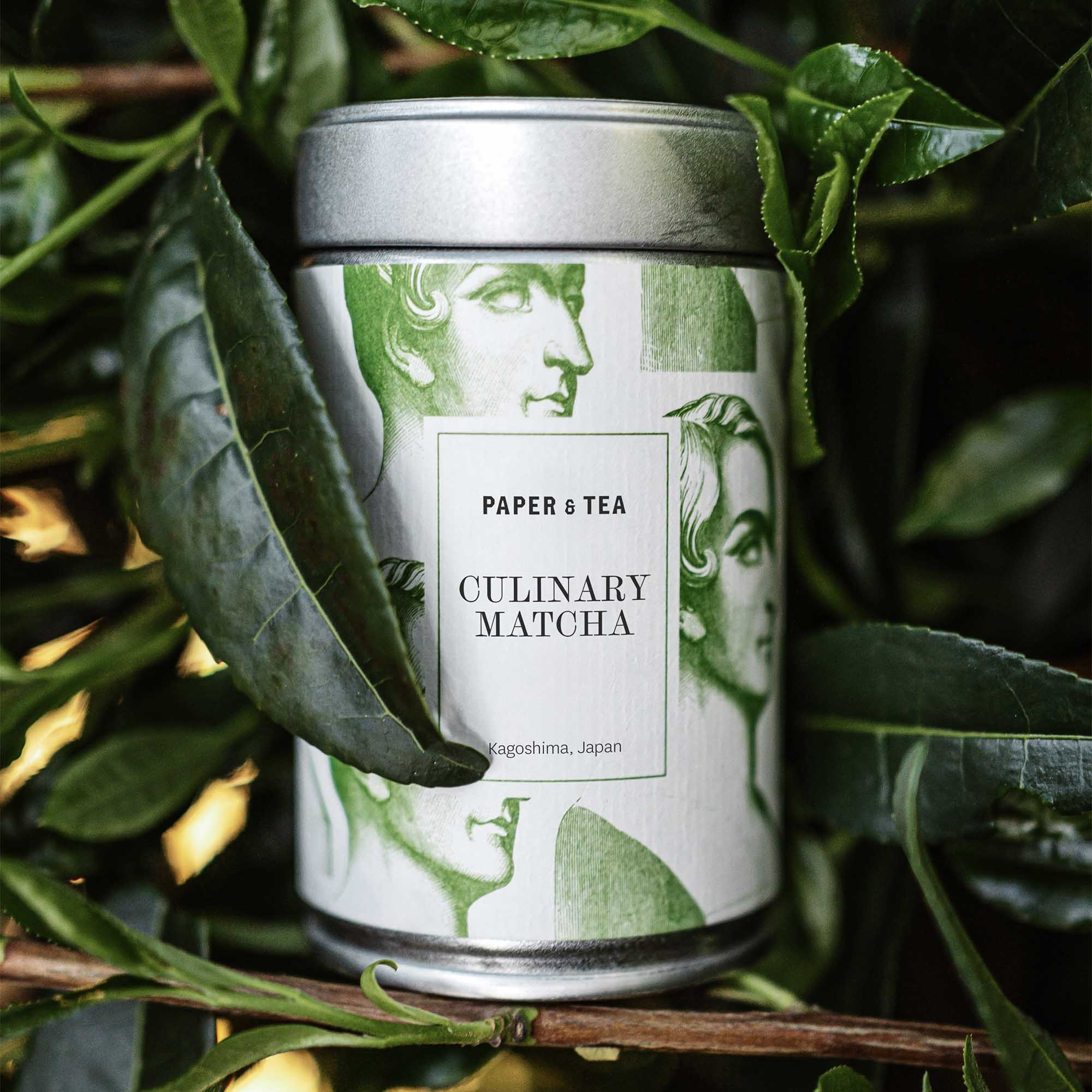 Metall-Dose mit Paper & Tea Culinary Matcha aus Kagoshima, Japan, umgeben von grünen Teeblättern.