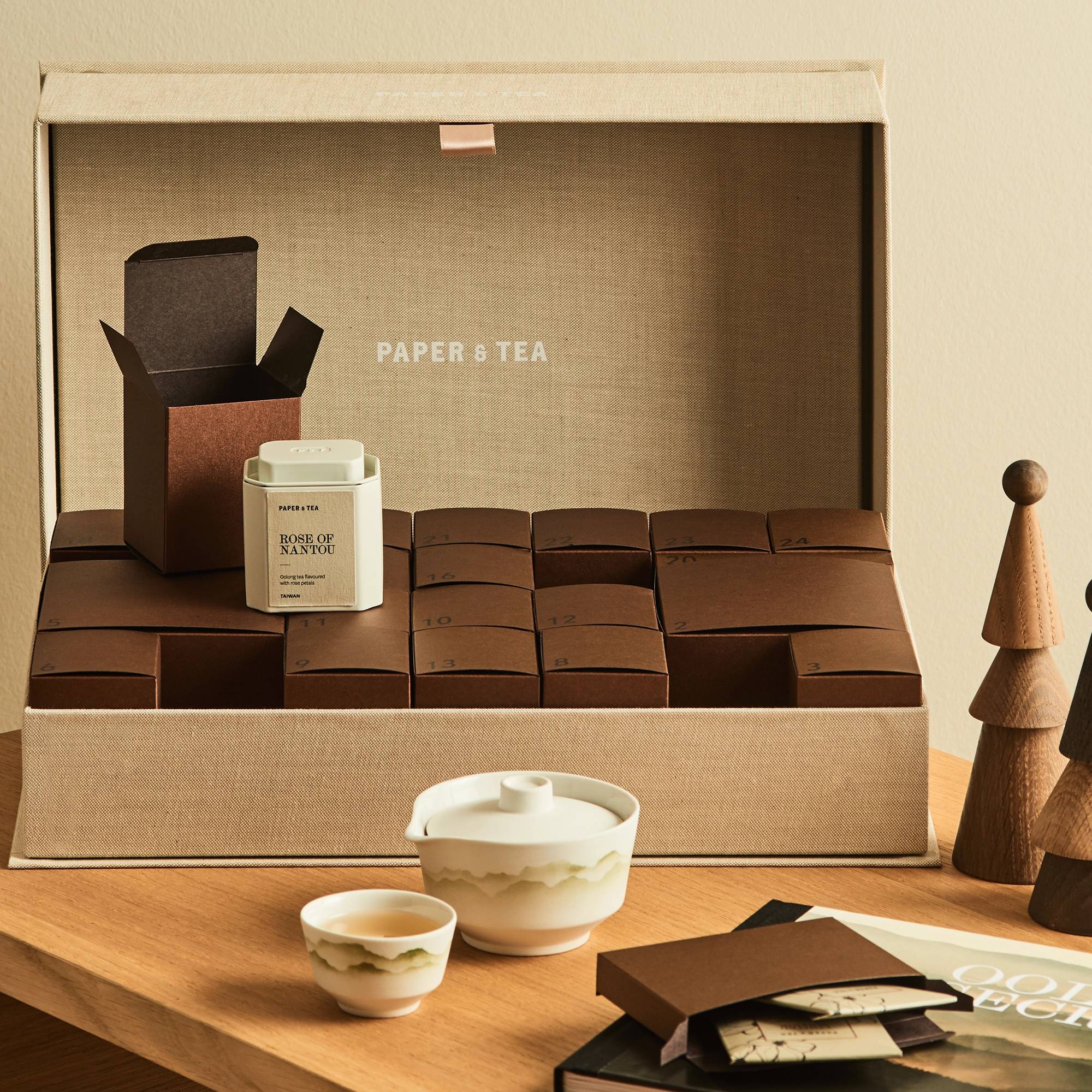 Elegantes Geschenkset: Stoffbox mit 24 Teeboxen, Oolong-Tee, zwei Tassen und Holzdekoration.