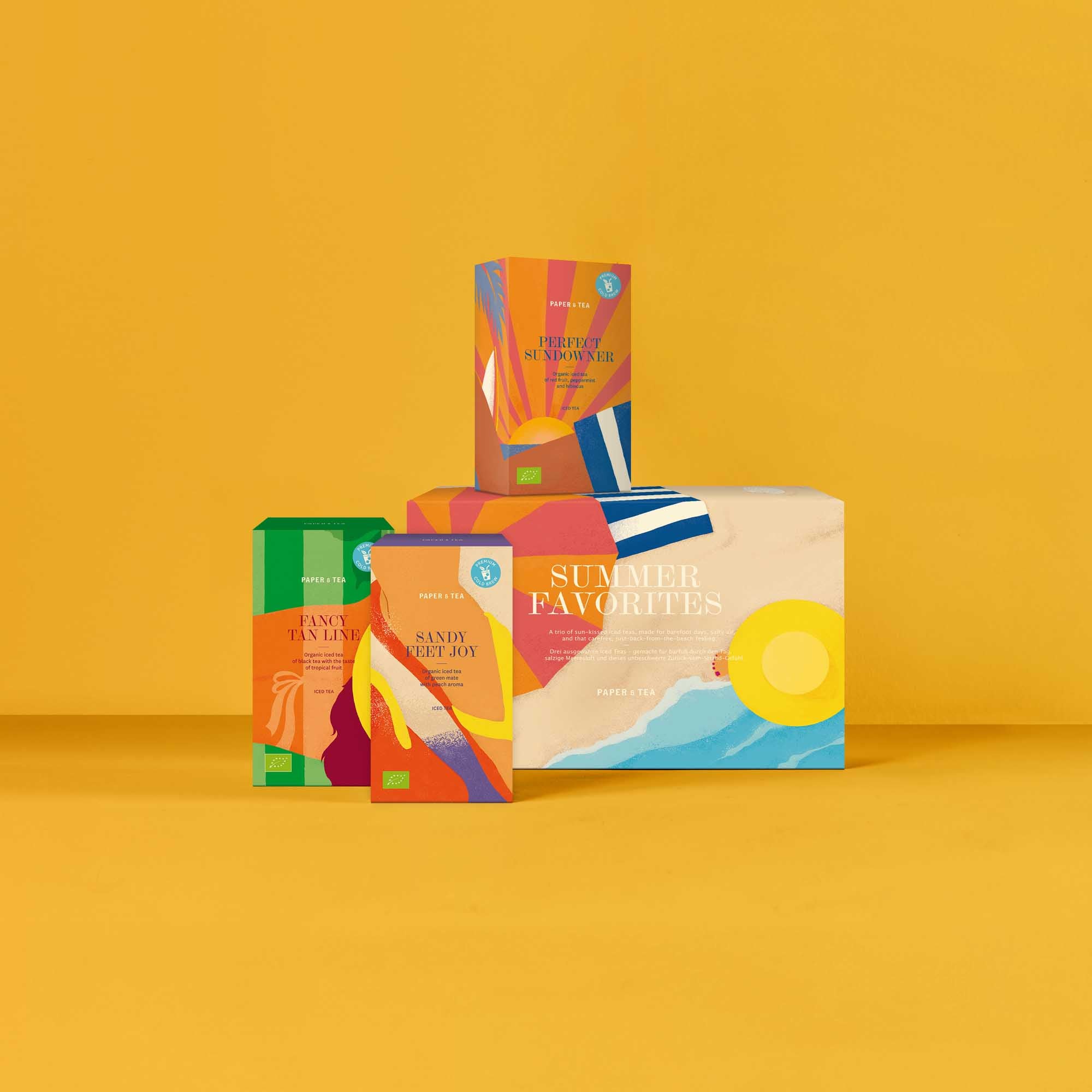 Vier bunte Packungen organischen Eistees von PAPER & TEA, vor gelbem Hintergrund.