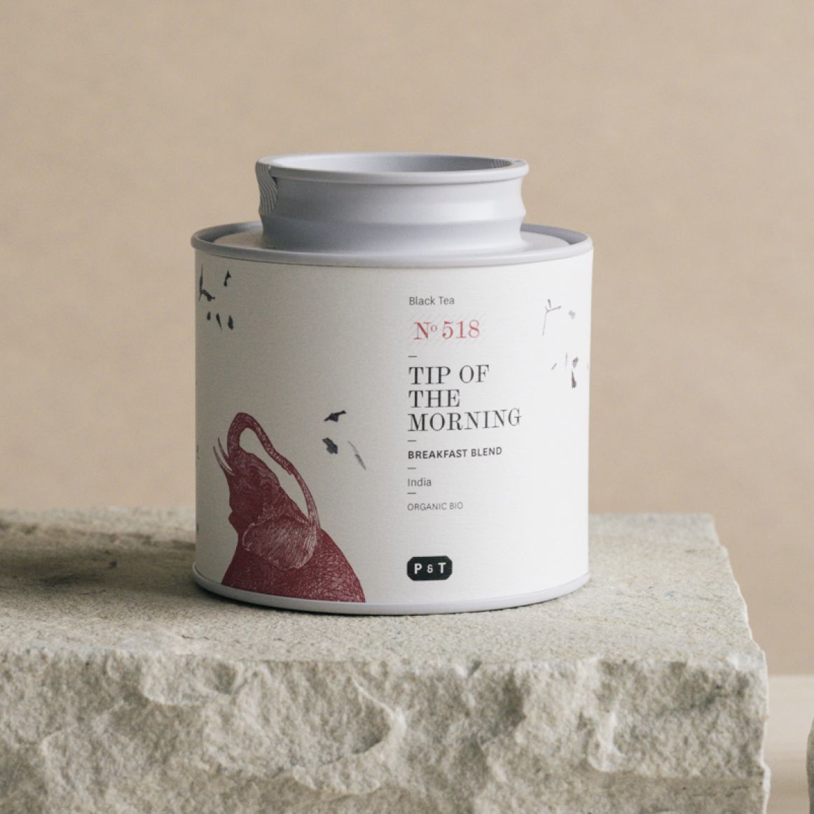 Weißer Teebehälter mit rotem Elefanten und grauem Deckel, auf Steinoberfläche, organischer schwarzer Tee 'Tip of the Morning'