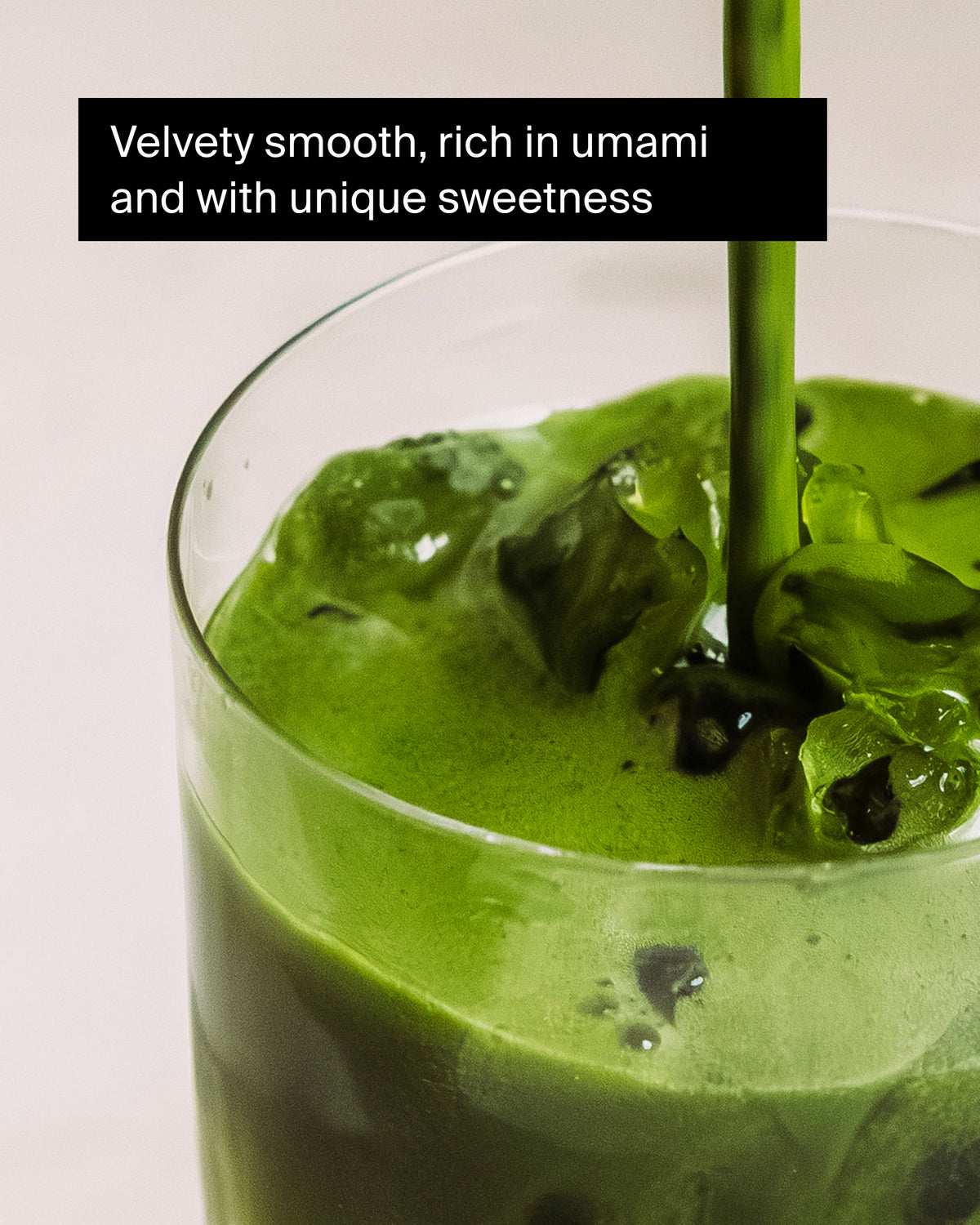 Klares Glas mit grünem Tee und Eiswürfeln, Flüssigkeit wird eingegossen, schaumige Oberfläche.