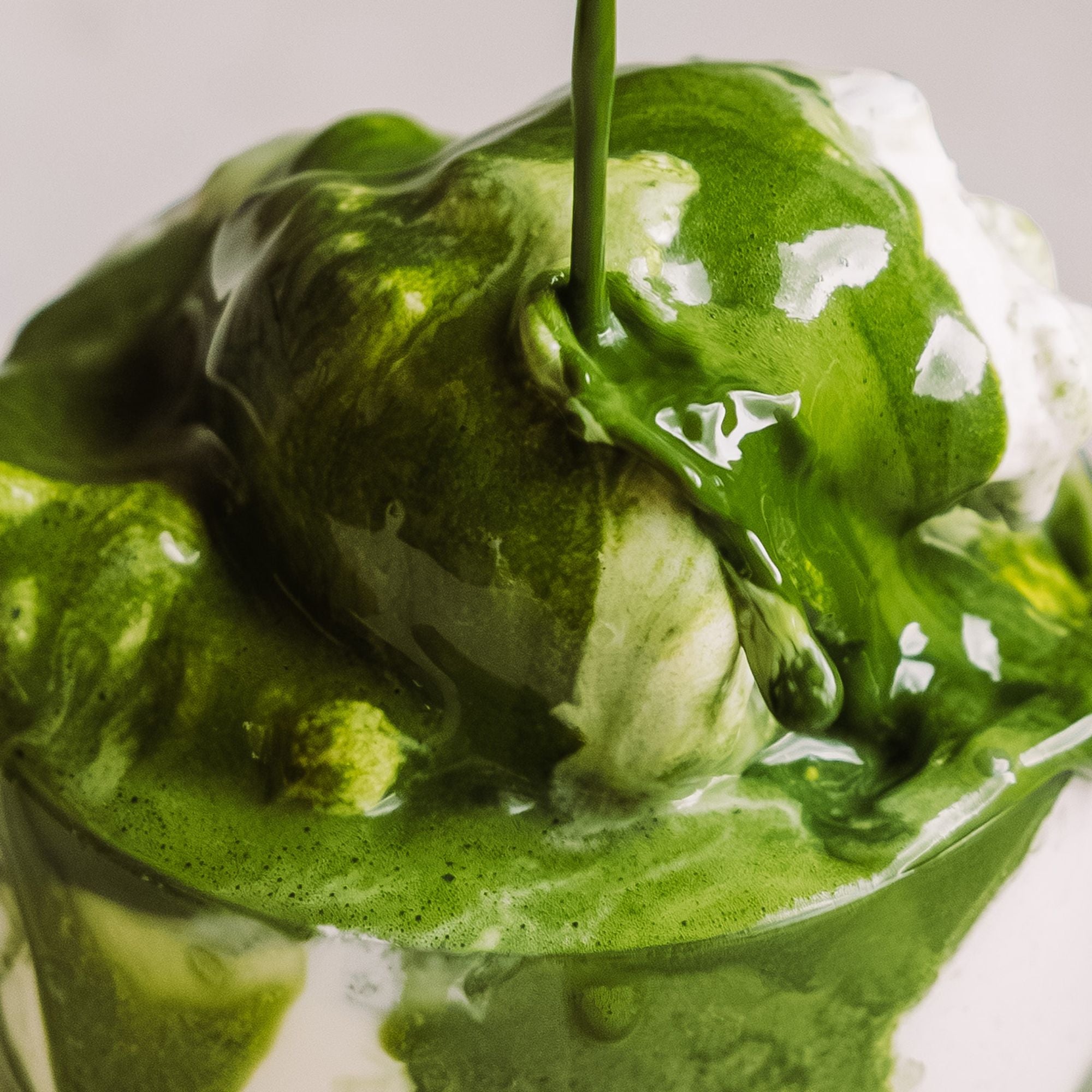 Vanilleeis mit dicker Matcha-Grünteesauce, die über das Eis fließt.