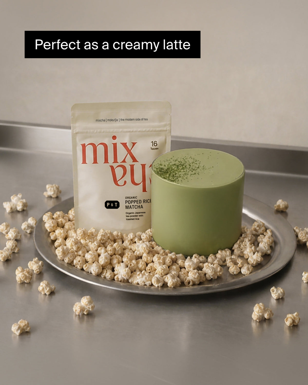 Cremiger Matcha-Latte in grünem Becher mit P&T Popped Rice Matcha auf Silbertablett.