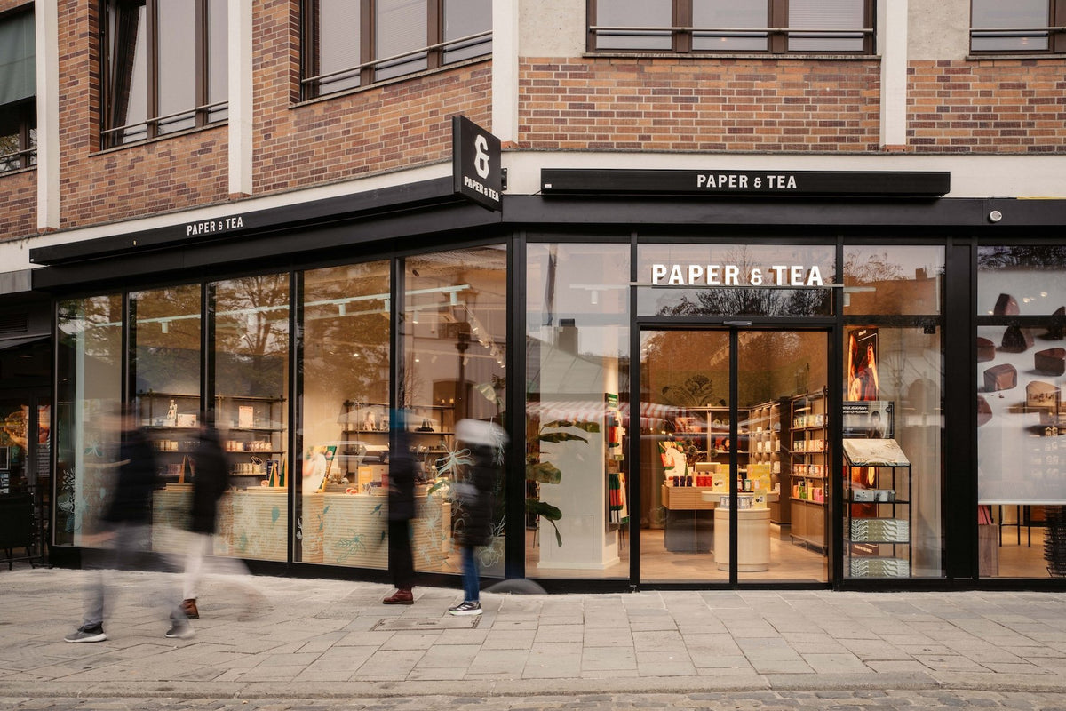 Modernes PAPER & TEA Ladengeschäft mit großen Glasfenstern und beleuchtetem Geschäftsschild Nummer 9.